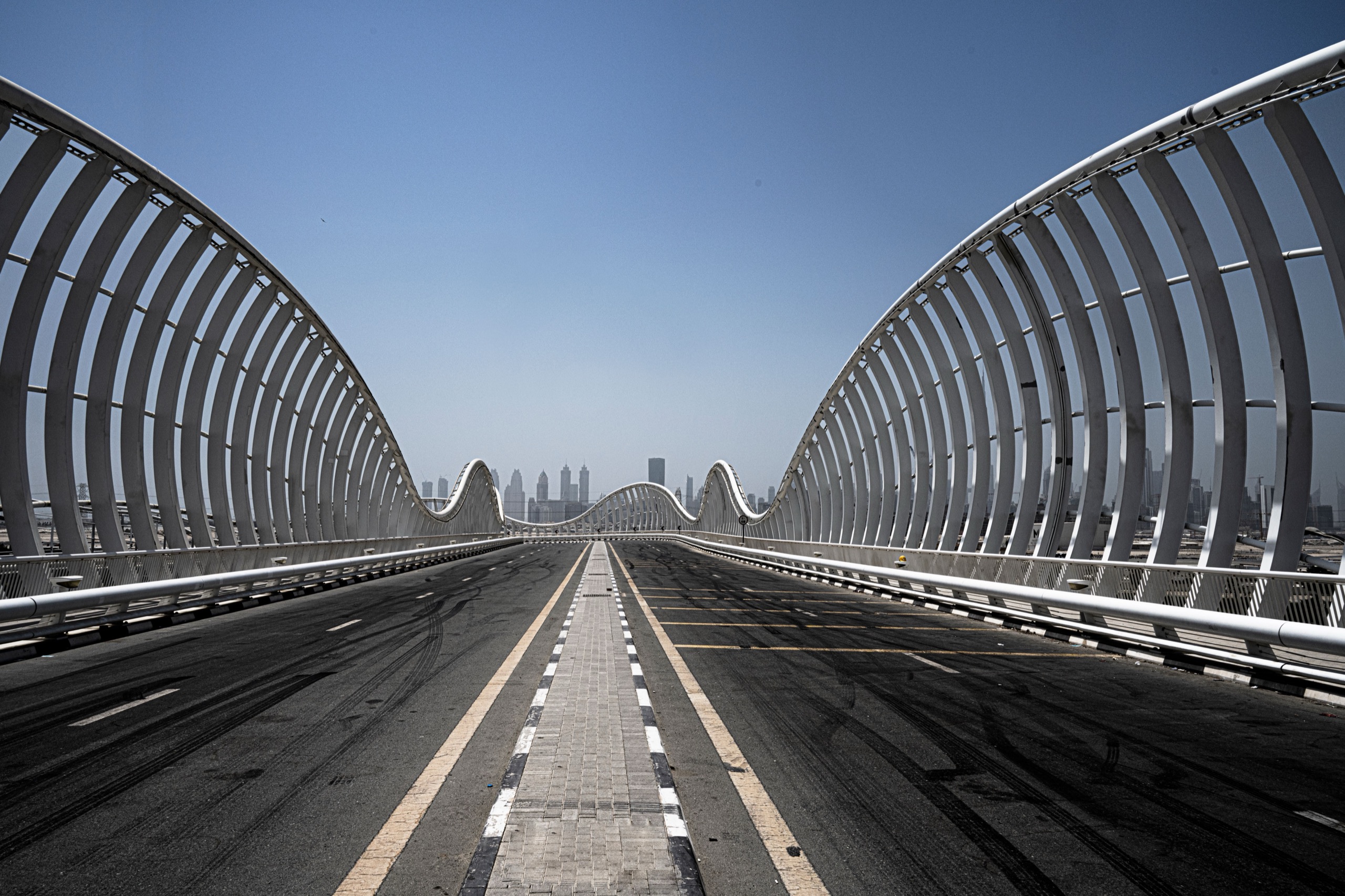 Meydan Bridge in daylight, white steel arches over the road under a clear sky